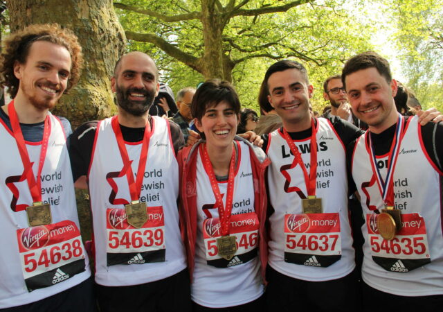 5 runners standing together with medals after marathon